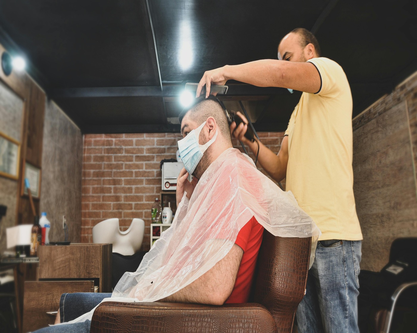 Barber finishing a cut under warm shop lighting